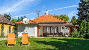 A house with a satellite dish, two orange lawn chairs, and a small patio area. - Vacation home Marie by Interhome (Balatonmariafurdo)