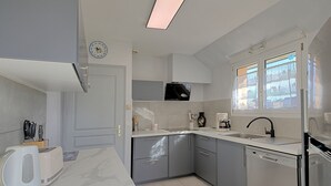 A modern kitchen with grey cabinets, a white countertop, a coffee maker, and a dishwasher. - Charme de Penvins by Interhome (Sarzeau)