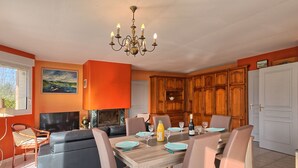A dining area with a wooden table set for four, a fireplace, and wooden cabinets. - Charme de Penvins by Interhome (Sarzeau)