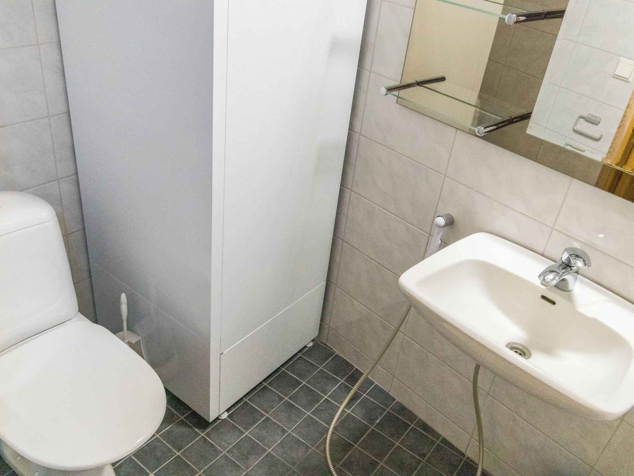 A small bathroom with a toilet, a sink, and a mirror.