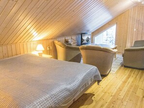 A cozy room with a bed, two armchairs, a table, and a television.