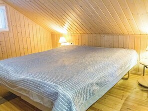 Un lit simple dans une pièce aux murs en bois et au plafond en pente.