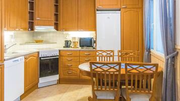 Une cuisine compacte avec des meubles en bois, une cuisinière, un four à micro-ondes et une table à manger avec des chaises.
