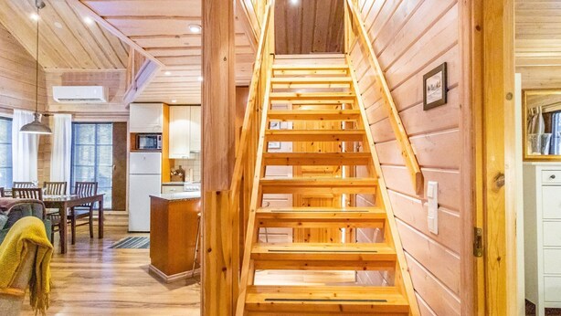 A wooden staircase leading to a loft bedroom with a view of the living area.