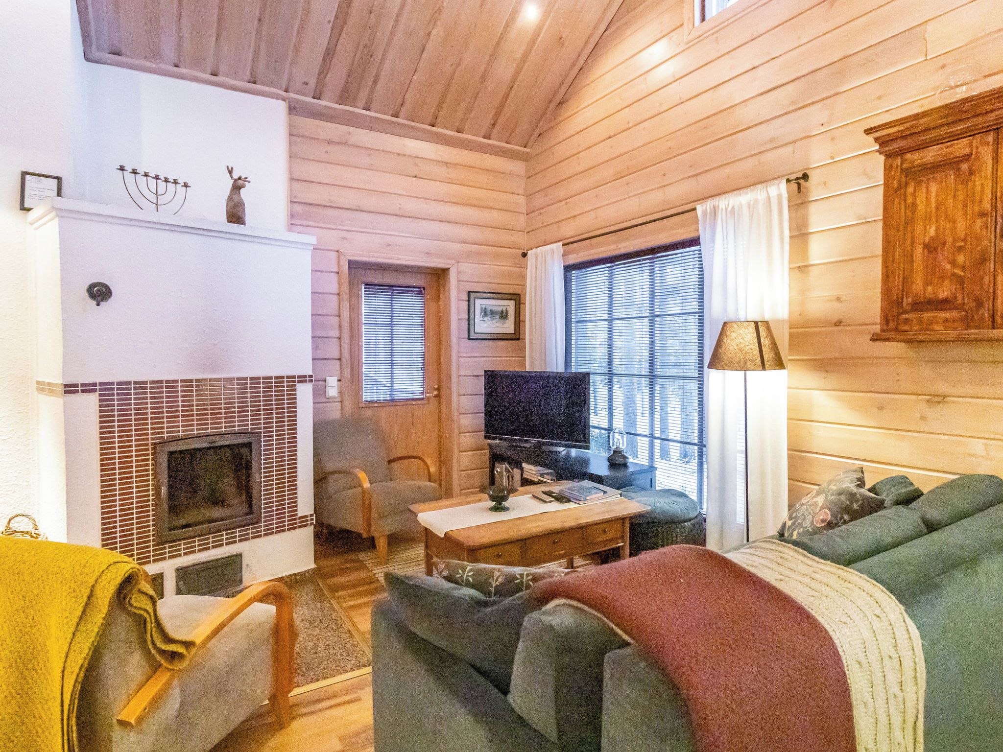 A cozy cabin interior with a fireplace, a television, and a comfortable seating area.