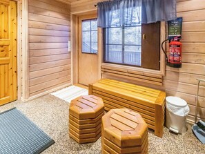 Un cuarto de sauna con bancos de madera, un extintor y una ventana con persianas.