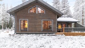 A wooden cabin with a gabled roof, large windows, and a deck.