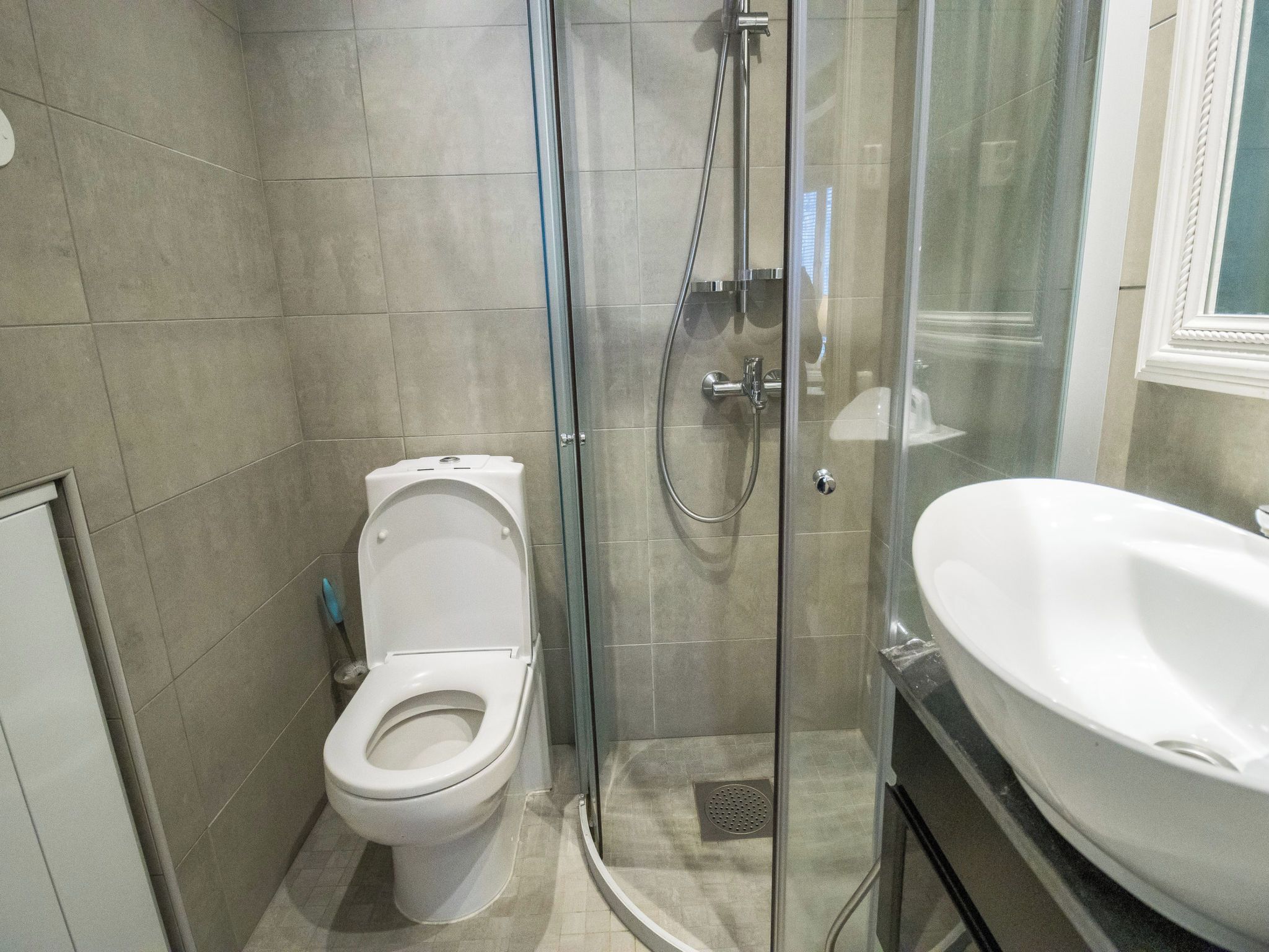 A modern bathroom with a glass-enclosed shower, a white toilet, and a large sink.