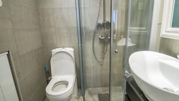 A modern bathroom with a glass-enclosed shower, a white toilet, and a large sink.