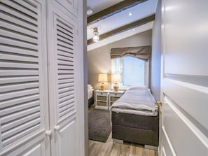 Een slaapkamer met een bed, nachtkastjes, een lamp en een raam met jaloezieën.
