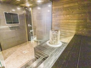 Un baño moderno con cabina de ducha de vidrio, piso de baldosas de mármol y una pared decorativa de madera.