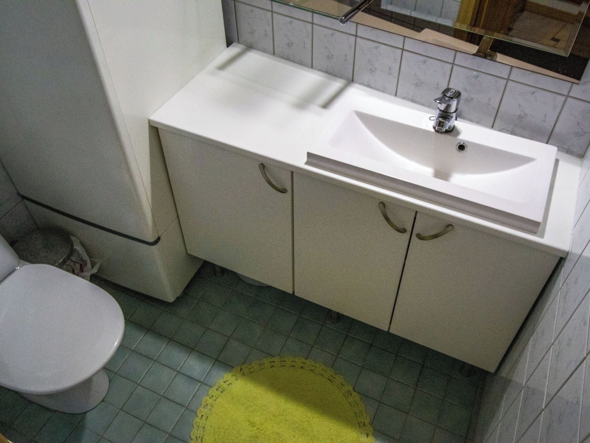 A bathroom with a toilet, sink, and cabinets.