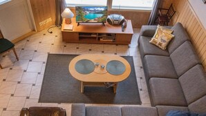 Una sala de estar moderna con un sofá, una mesa de centro, una televisión y vistas a un lago a través de una ventana.