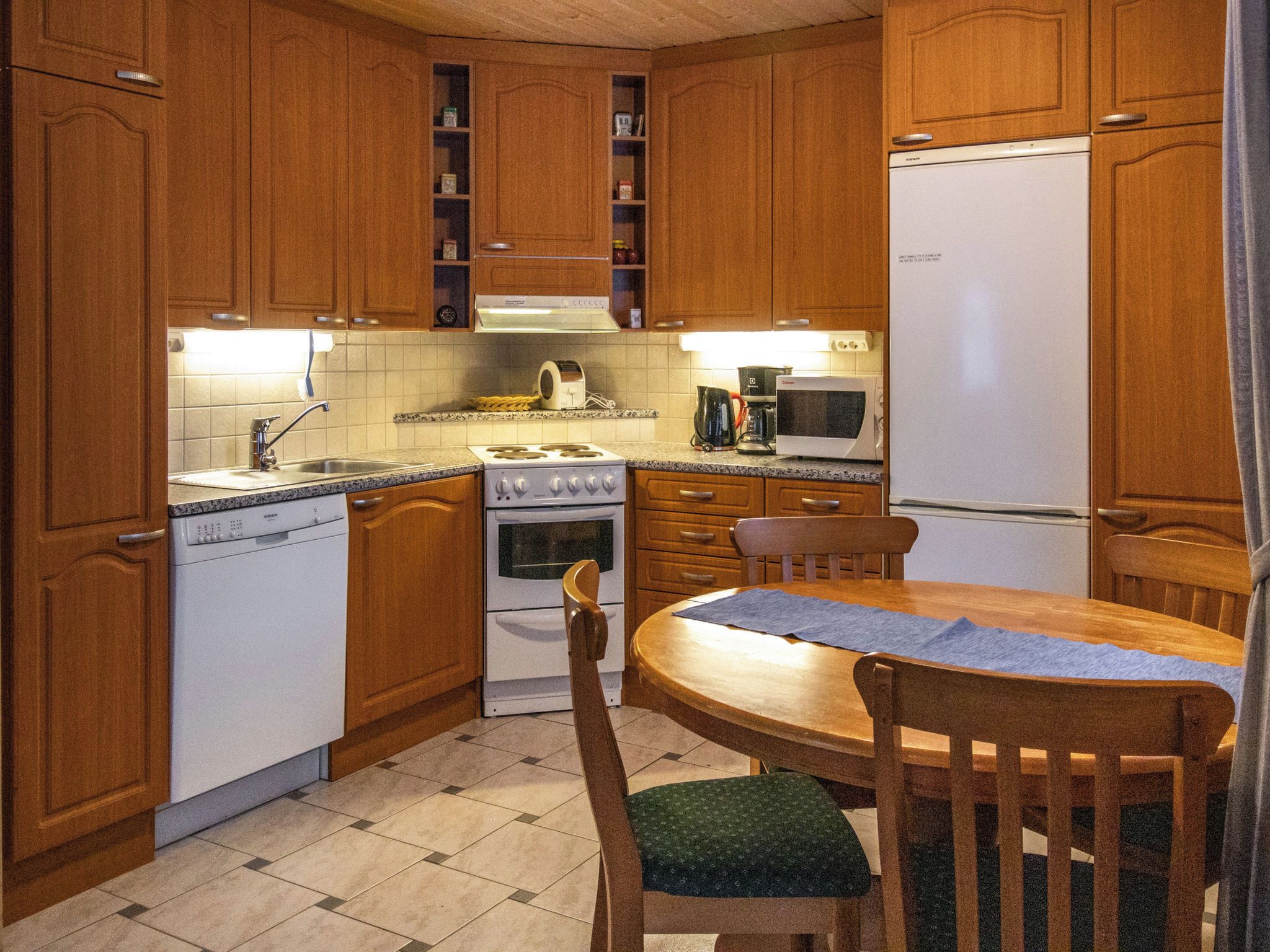 A compact kitchen with wooden cabinets, a stove, a dishwasher, and a microwave.