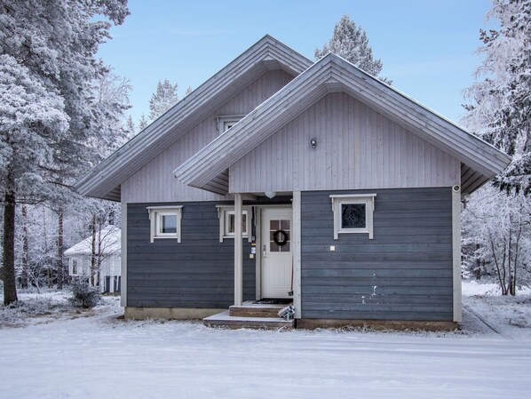 A two-story house with a front porch, a garage, and a snow-covered landscape.