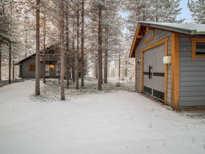 Eine Hütte mit Garage, umgeben von schneebedeckten Bäumen.