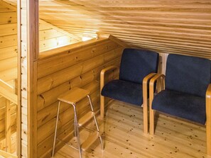A wooden interior with two blue upholstered chairs, a small wooden stool, and a wooden bench.