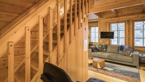 Un interior de madera con una escalera, un sofá y un televisor.