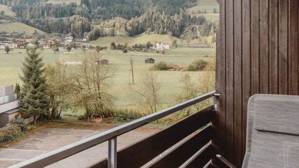 Un balcon donnant sur un paysage rural, avec des maisons et des arbres.