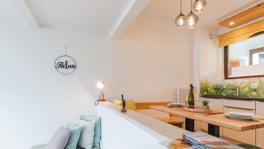 Une cuisine moderne avec un coin repas, un panneau fixé au mur et un magazine posé sur le comptoir.
