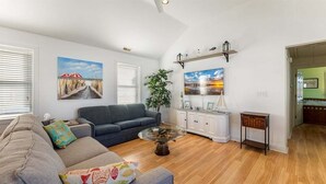 A living room with a sofa, a coffee table, and a painting on the wall. - 2 Bedroom Condo Only Steps to the Beach! (North Wildwood)