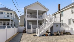 A two-story house with a balcony, a staircase, and a fenced yard. - 2 Bedroom Condo Only Steps to the Beach! (North Wildwood)