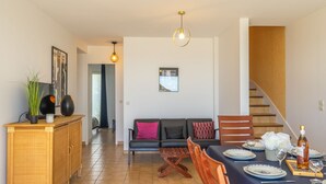 Ein Essbereich mit Tisch für vier Personen, einer Couch, einem Holzschrank und einer Treppe.