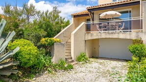 Ein zweistöckiges Haus mit überdachter Terrasse, Garage und einer Treppe, die zu der oberen Etage führt.