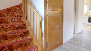 A staircase with floral carpet, a wooden door, and a kitchen area in the background. - Chalet Dori by Interhome (Interlaken)