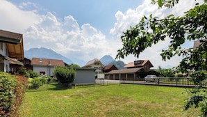 A residential area with houses, a fenced yard, and mountains in the background. - Chalet Dori by Interhome (Interlaken)