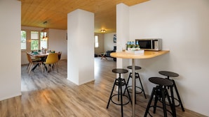 A modern kitchen with a wooden ceiling, a dining area with a table and chairs, and a bar area with stools. - Chalet Dori by Interhome (Interlaken)
