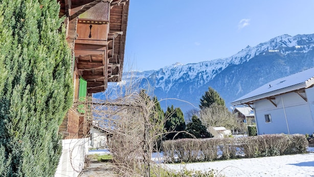 A traditional wooden chalet with a sloped roof, surrounded by snow-covered ground and mountains in the background. - Chalet Dori by Interhome (Interlaken)