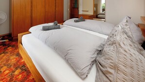 A bedroom with two beds, a wooden wardrobe, a mirror, and a fan. - Chalet Dori by Interhome (Interlaken)