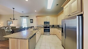 Una cucina moderna con piani in granito, elettrodomestici in acciaio inossidabile e mobili in legno chiaro.