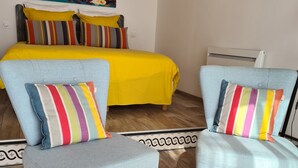 A room with a bed, two armchairs, a table, and a painting on the wall. - PALMIER *** studio with garden and parking (Le Bois-Plage-en-Ré)