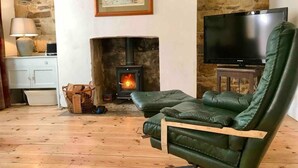 A cozy living room with a fireplace, a television, and a comfortable green leather chair. - Beachfront Apartment With Woodburner & Courtyard (St Leonards-On-Sea)