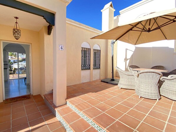 A covered patio with wicker furniture and a tiled floor.