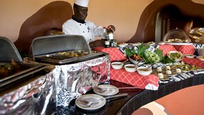 Una mesa de buffet con diversos platos y un chef preparando comida.