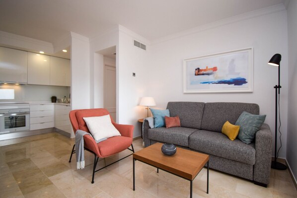 Un salon moderne avec un canapé gris, un fauteuil rouge et une table basse en bois.
