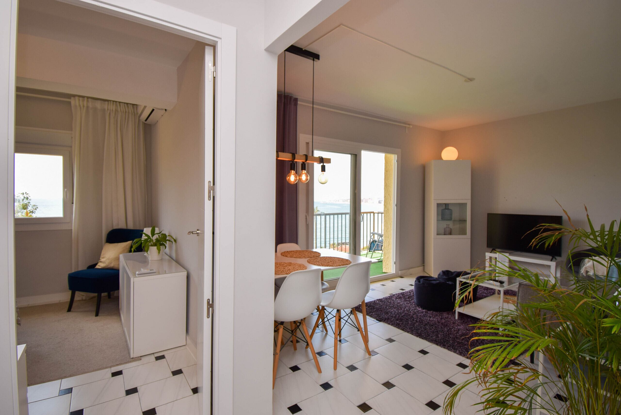 Ein modernes Wohnzimmer mit Essbereich, Fernseher und Balkon mit Blick.