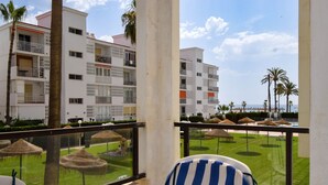 Ein Balkon mit Blick auf einen Poolbereich, Palmen und ein Gebäude mit Balkonen.