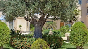 A well-maintained garden with a large tree, a Buddha statue, and various shrubs and flowers. - Ref: 240  Modern beautiful apartment with amazing sea views (Fuengirola)