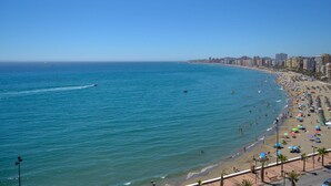 A coastal cityscape with a wide beach, clear blue sea, and a row of buildings along the shore. - Ref: 240  Modern beautiful apartment with amazing sea views (Fuengirola)