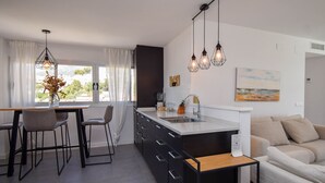 A modern kitchen with a central island, bar stools, pendant lighting, and a view of the outdoors. - Ref: 307 Modern beachfront apartment in Torreblanca with stunning sea views (Fuengirola)