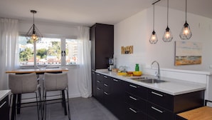 A modern kitchen with a large island, bar stools, and pendant lighting. - Ref: 307 Modern beachfront apartment in Torreblanca with stunning sea views (Fuengirola)