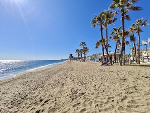 A beach with palm trees, a lifeguard tower, and a clear blue sky. - Ref: 233 Modern 3 bedroom apartment next to the beach in La Cala (La Cala de Mijas)
