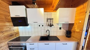 Eine kompakte Küche mit weißen Schränken, einem schwarzen Spülbecken und einem Herd.