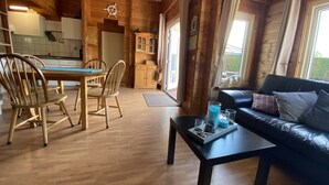 Ein Holzblockhaus mit Essbereich, Küche und Wohnzimmer.