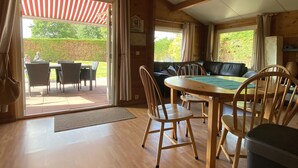 Ein Holzinterieur mit Essbereich, einer Couch und Blick ins Freie.