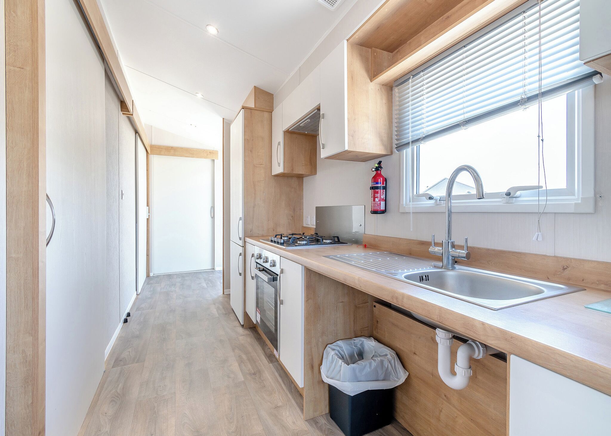A modern kitchen with a wooden countertop, stainless steel sink, and a window with blinds.